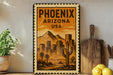 A vintage-style metal sign with a desert cityscape and mountains, featuring the text "PHOENIX ARIZONA USA" prominently displayed.