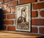 A metal sign featuring a sea lion on a brick wall.