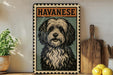 A framed illustration of a Havanaese dog is displayed on a shelf, accompanied by a wooden cutting board, a potted plant, and some lemons.