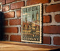 A vintage-style postage stamp depicting the Leipzig cityscape, with the word "GERMANY" printed below it, is displayed on a brick wall.