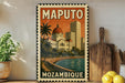 A vintage-style poster of Maputo, Mozambique, featuring a cityscape with a dome-shaped building and palm trees, displayed on a wall next to a wooden cutting board and a potted plant.