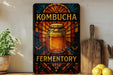 A colorful stained glass-style sign for "Kombucha Fermentation" is displayed on a shelf, accompanied by a wooden cutting board and a potted plant.