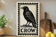 a black and white illustration of a crow on a wooden surface, with a wooden cutting board and a potted plant nearby.