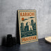 A metal sign with the text "KARACHI PAKISTAN" and an illustration of a city skyline, placed on a gray countertop next to some black camera lenses.