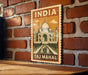 A vintage-style metal sign with the text "INDIA Taj Mahal" and an illustration of the Taj Mahal, a famous mausoleum in India.