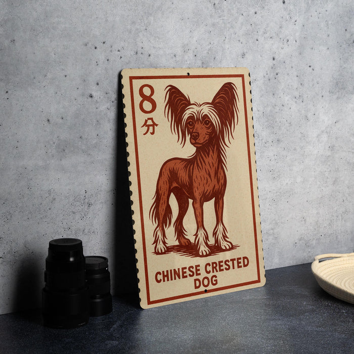 A Chinese Crested Dog illustration on a wooden postcard or sign, placed on a table next to some black camera lenses.