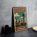 A vintage-style metal stamp depicting the Düsseldorf Tower in Germany, with a cityscape and a cloudy sky in the background.