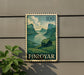 a postage stamp with a landscape scene, mounted on a wall next to a plant.