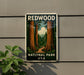 A vintage-style sign for Redwood National Park in the USA, featuring a scenic image of towering redwood trees and a winding path through the forest.