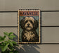 A framed image of a dog, specifically a Havanaese dog, is displayed on a wall.