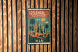 A vintage-style metal sign with the text "LOS ANGELES CALIFORNIA USA" displayed on a wooden wall.