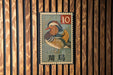 A metal stamp featuring a colorful illustration of a bird, likely a duck, with the number 10 and some text in a foreign language.