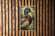 A framed illustration of a duck is displayed on a wooden wall.