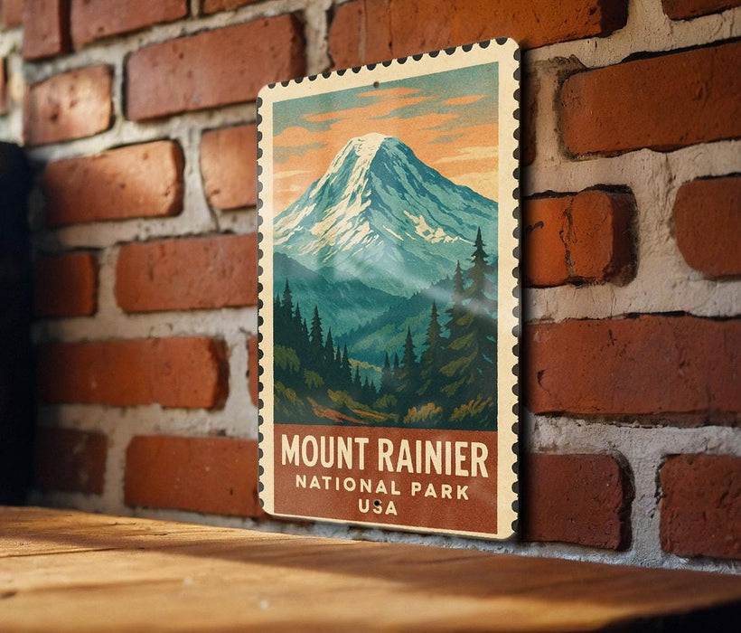 A vintage-style metal sign depicting a mountain landscape with pine trees and a snow-capped peak, mounted on a brick wall.
