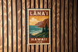 A vintage-style metal sign with the text "LANA'I" and "HAWAII" printed on it, hanging on a wooden wall.