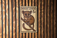 A wooden wall with a framed image of a brown animal, likely a rodent or small mammal, sitting on a branch.