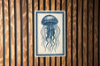 a blue and white illustration of a jellyfish on a wooden surface.