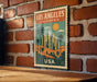 A vintage-style metal sign with a cityscape and palm trees, mounted on a brick wall.
