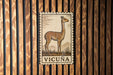a wooden wall with a framed illustration of a llama, which is the main focus of the image.