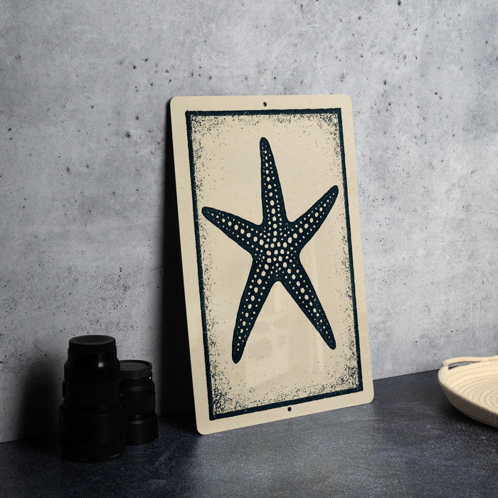a framed picture of a starfish on a wall, with a stack of black camera lenses and a woven basket placed next to it.