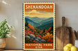 a framed vintage-style stamp depicting a scenic landscape with mountains, trees, and a river, placed on a shelf next to a wooden cutting board and some potted plants.