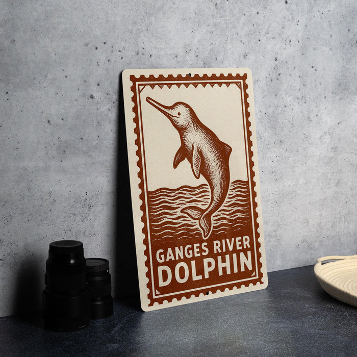 a sign with a dolphin illustration and the text "Ganges River Dolphin" on it, placed on a table next to some black camera lenses.