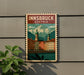 A vintage-style postage stamp depicting the town of Innbruck, Austria, with colorful buildings and a mountain backdrop.