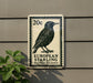 a postage stamp with a bird on it, mounted on a wall.