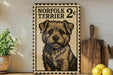 a framed poster of a dog, specifically a Norfolk Terrier, with a price tag of 2 cents. The poster is displayed on a shelf next to a wooden cutting board and some lemons.