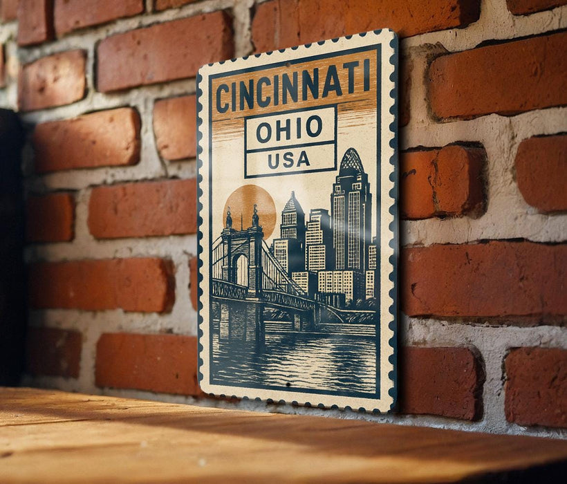 A vintage-style postage stamp featuring the cityscape of Cincinnati, Ohio, USA, hanging on a brick wall.
