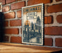 A vintage-style postage stamp featuring the cityscape of Cincinnati, Ohio, USA, hanging on a brick wall.