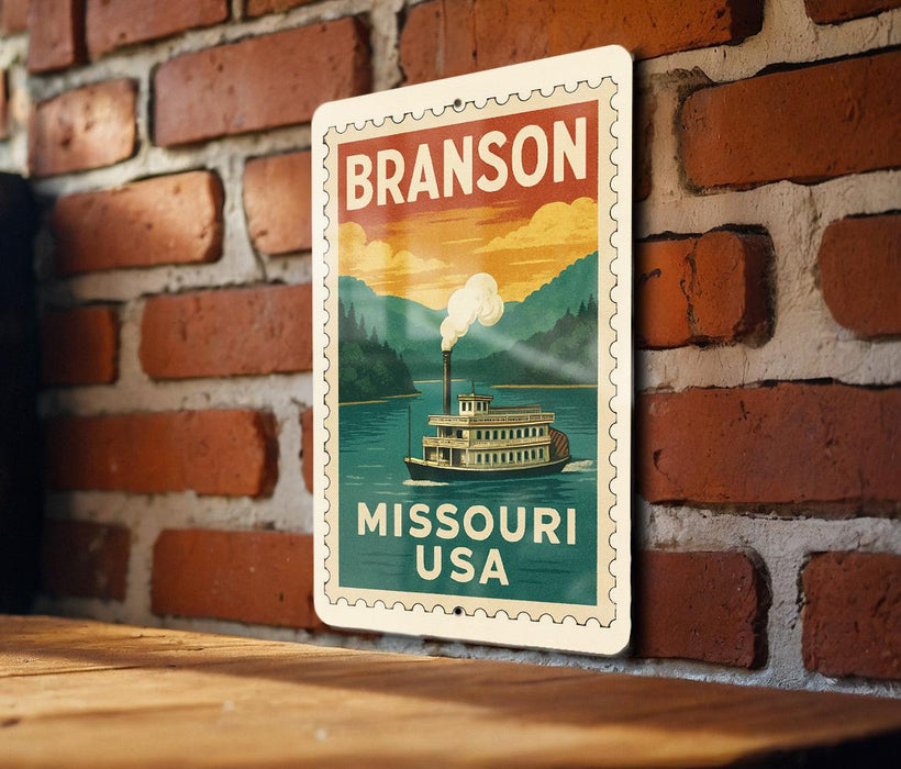 A vintage-style metal sign with the text "BRANSON MISSOURI USA" and an illustration of a steamboat on a river.