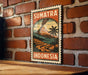 A vintage-style postage stamp from Sumatra, Indonesia, featuring a tropical landscape with a volcano and palm trees.