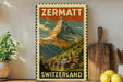 A vintage-style poster of the Matterhorn mountain in Switzerland, featuring a village in the foreground and the text "ZERMATT SWITZERLAND" at the bottom.