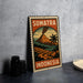 A metal sign with a vintage-style illustration of a Sumatra volcano, surrounded by tropical elements, is displayed on a gray wall.