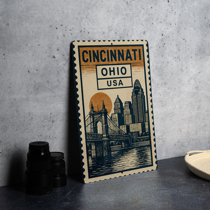 A metal sign with a cityscape illustration and the text "CINCINNATI OHIO USA" is displayed on a table.