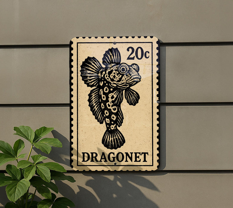 a sign with a black and white illustration of a fish, which appears to be a dragonnet. The sign is mounted on a wall, and there is a plant to the left of the sign.