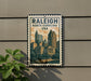 A metal sign with the text "RALEIGH NORTH CAROLINA USA" and an illustration of a city skyline, mounted on a wall.