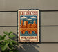 A metal sign with a colorful illustration of a city skyline and a bridge, mounted on a wall.