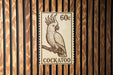 A stamp-like sign featuring a detailed illustration of a cockatoo bird perched on a branch.
