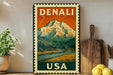 A vintage-style metal sign with a mountain landscape and text, mounted on a wall next to a wooden cutting board and some potted plants.