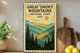 A framed poster of the Great Smoky Mountains National Park in the United States, featuring a scenic mountain landscape with pine trees and a sun in the sky.