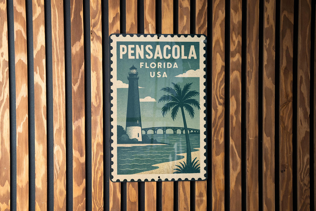 A vintage-style metal sign with the text "PENSACOLA FLORIDA USA" and a lighthouse illustration, mounted on a wooden wall.