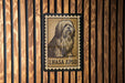 a wooden wall with a framed stamp-like artwork depicting a dog.