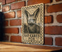 A wooden sign with a bat-eared fox illustration is mounted on a brick wall.