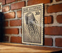 a wooden table with a framed illustration of a jellyfish on it, mounted on a brick wall.