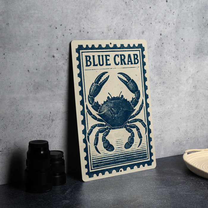 A metal sign with a blue crab illustration on it, placed on a table next to some black containers.