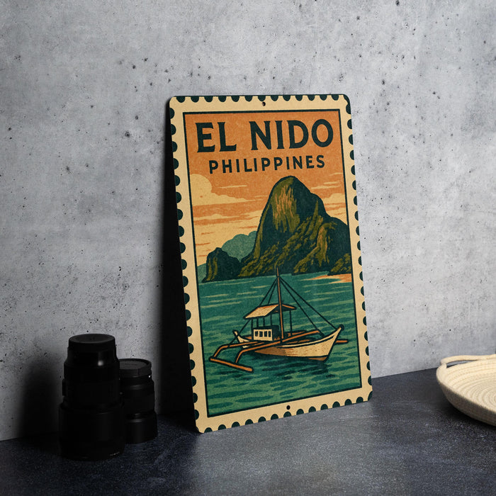 A vintage-style metal sign with the text "EL NIDO PHILIPPINES" and an illustration of a boat on a body of water, set against a backdrop of mountains.
