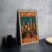 A metal sign with a stylized illustration of Atlanta, Georgia, featuring the city's skyline and highway.
