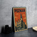 A metal sign with the text "POZNAN POLAND" and an illustration of a castle-like building, placed on a table next to some black camera lenses.